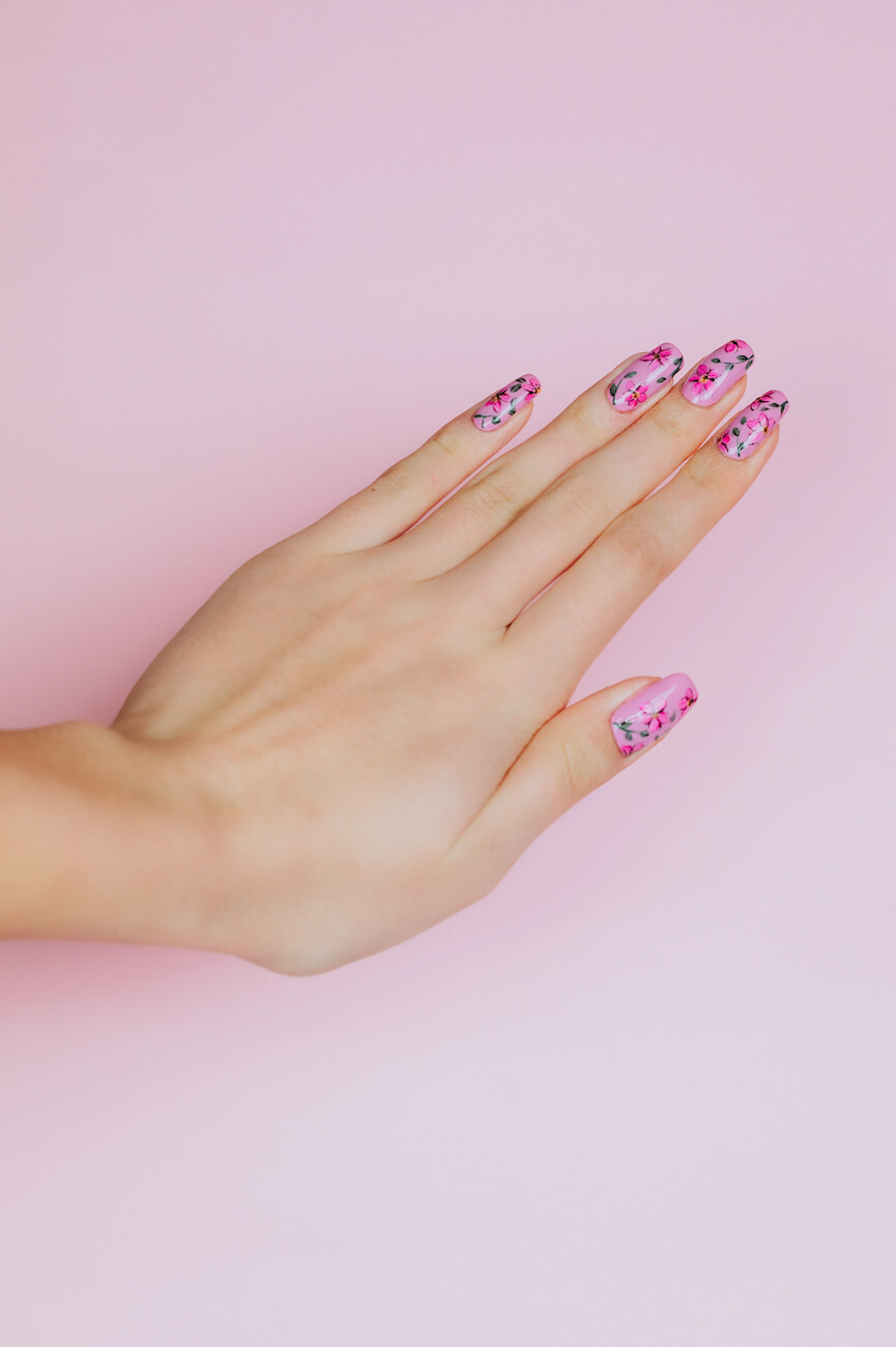 Kobieca dłoń z różowymi paznokciami z ozdobami
